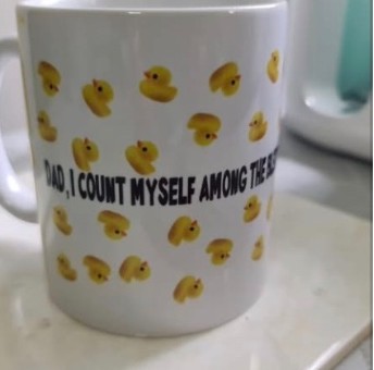 White mug printed with a playful message and duckling pattern